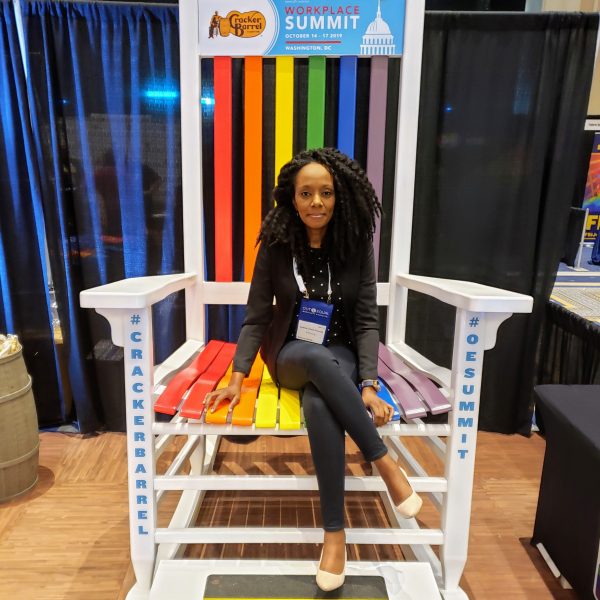 Jenny Francois sitting on an oversized rainbow-colored chair